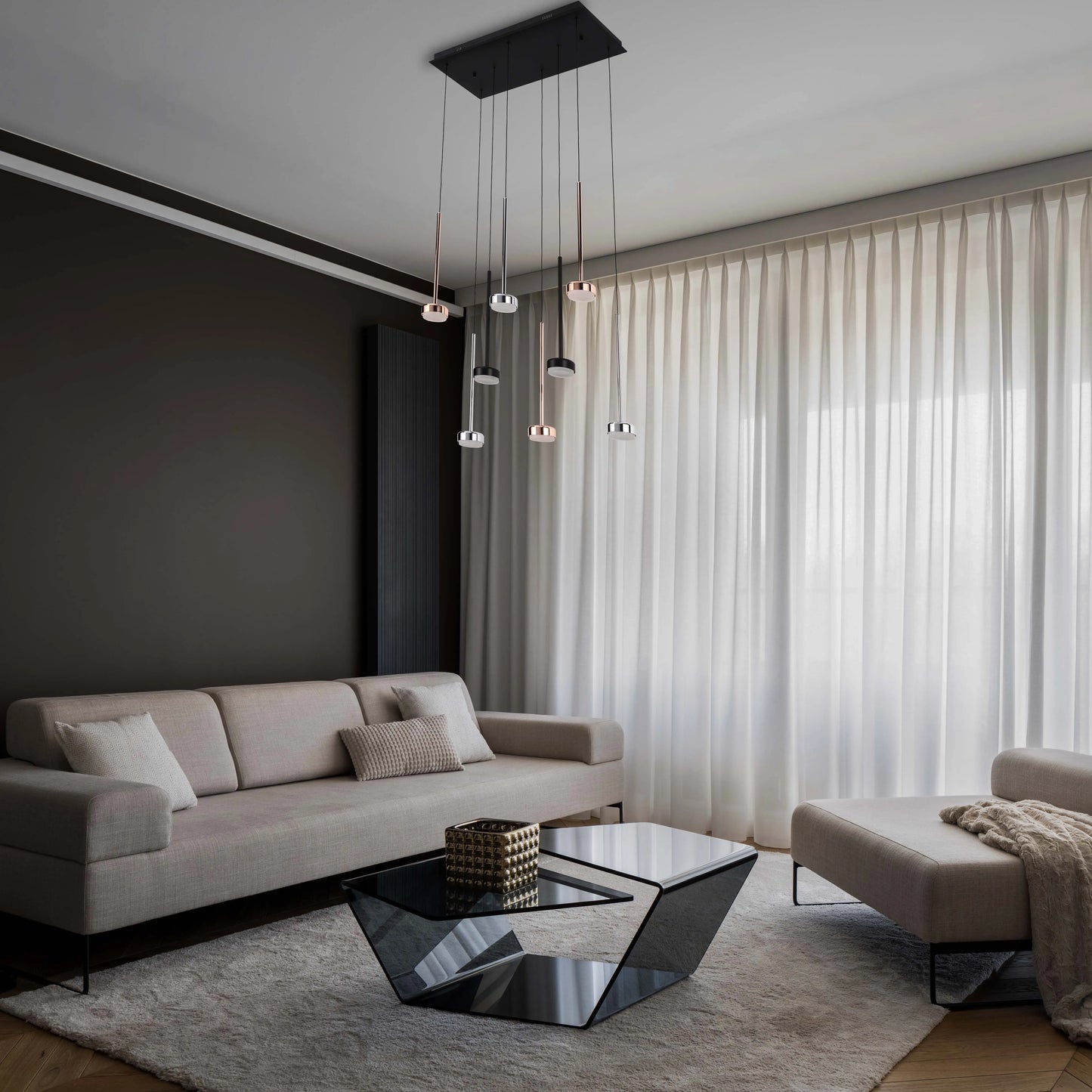 Modern pendant lighting with black ceiling rose hangs above a sleek glass coffee table in a contemporary living room.