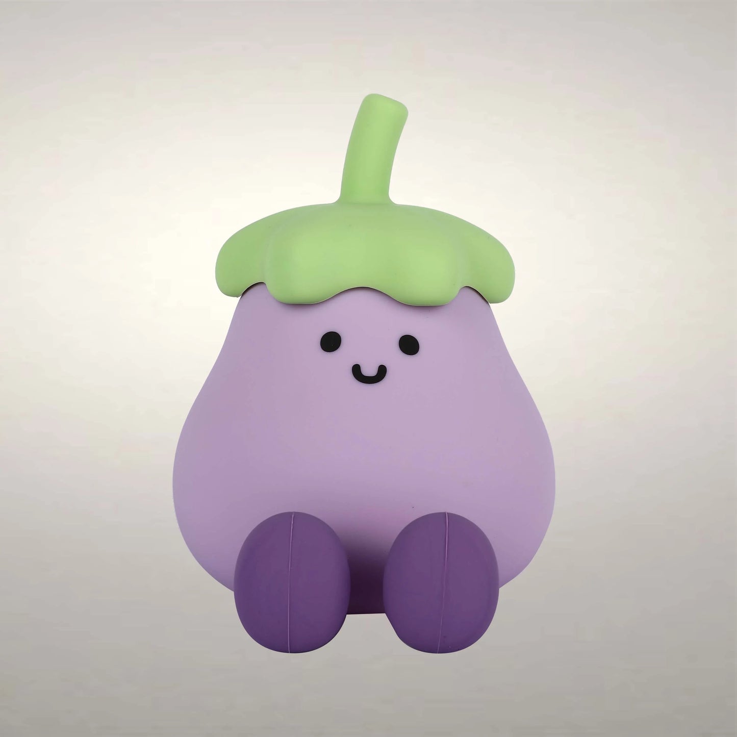 Soft, even lighting highlights the cute, cartoonish design of a smiling, purple eggplant with green top and darker purple legs.