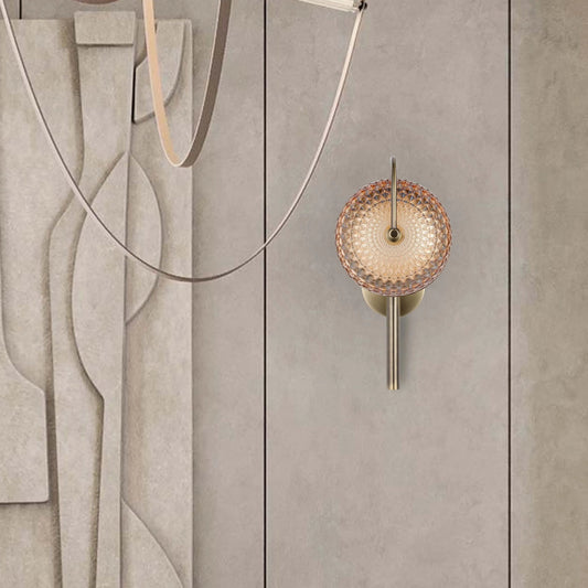 An ornate wall lamp, featuring an amber patterned diffuser and a brass-coloured mount.