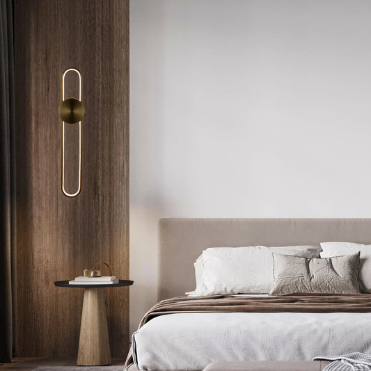 Elegant wall lighting: A gold, capsule-shaped light fixture illuminates a modern bedroom setting with warm, ambient light.