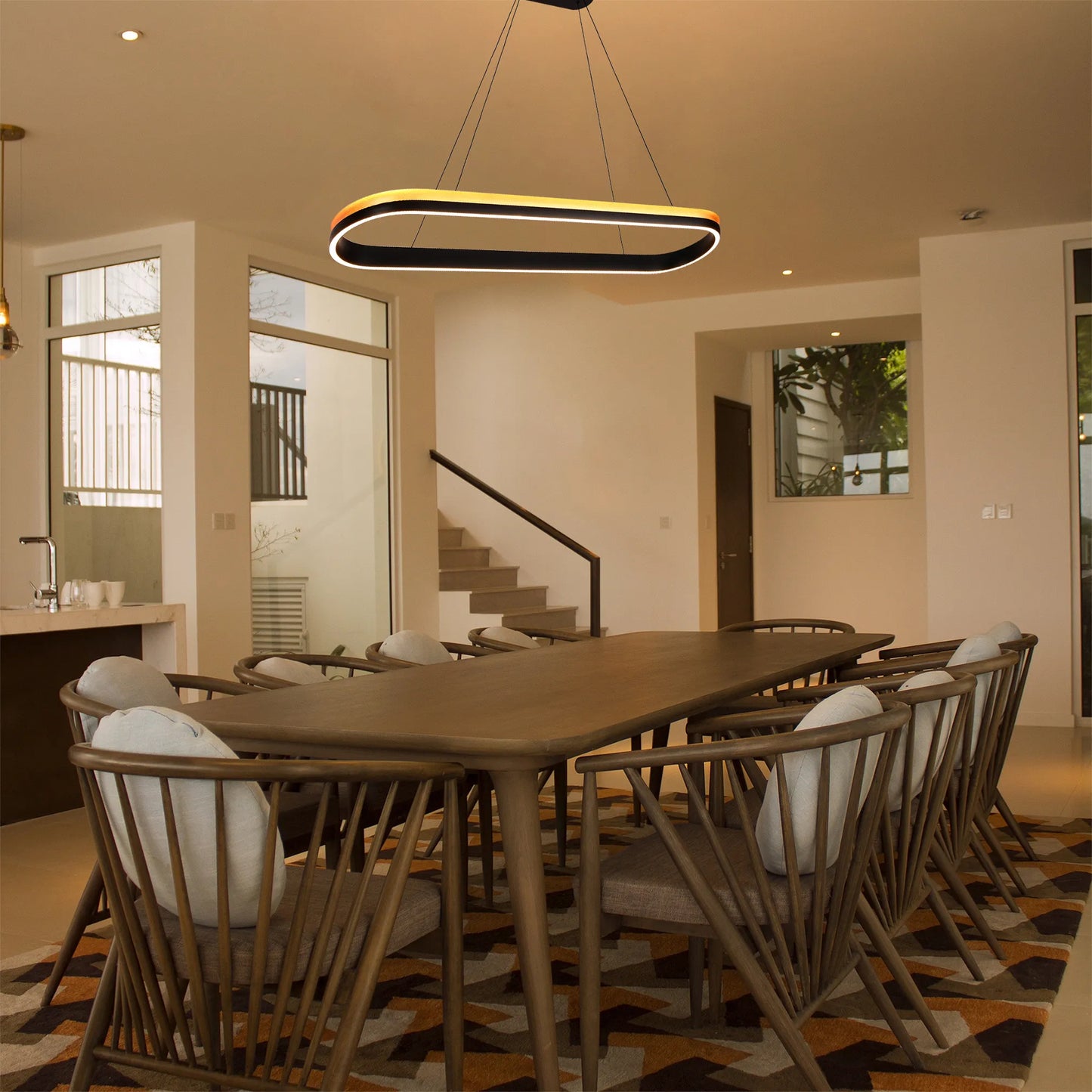 Contemporary, suspended LED light fixture illuminates a dining space. Warm light and sleek design.