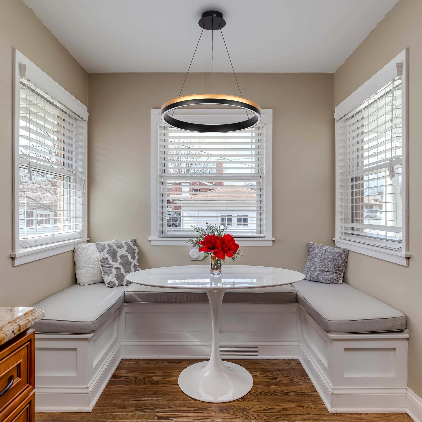 A modern, ring-shaped pendant light is the focal point above a breakfast nook, offering ambient illumination and a sleek design aesthetic.