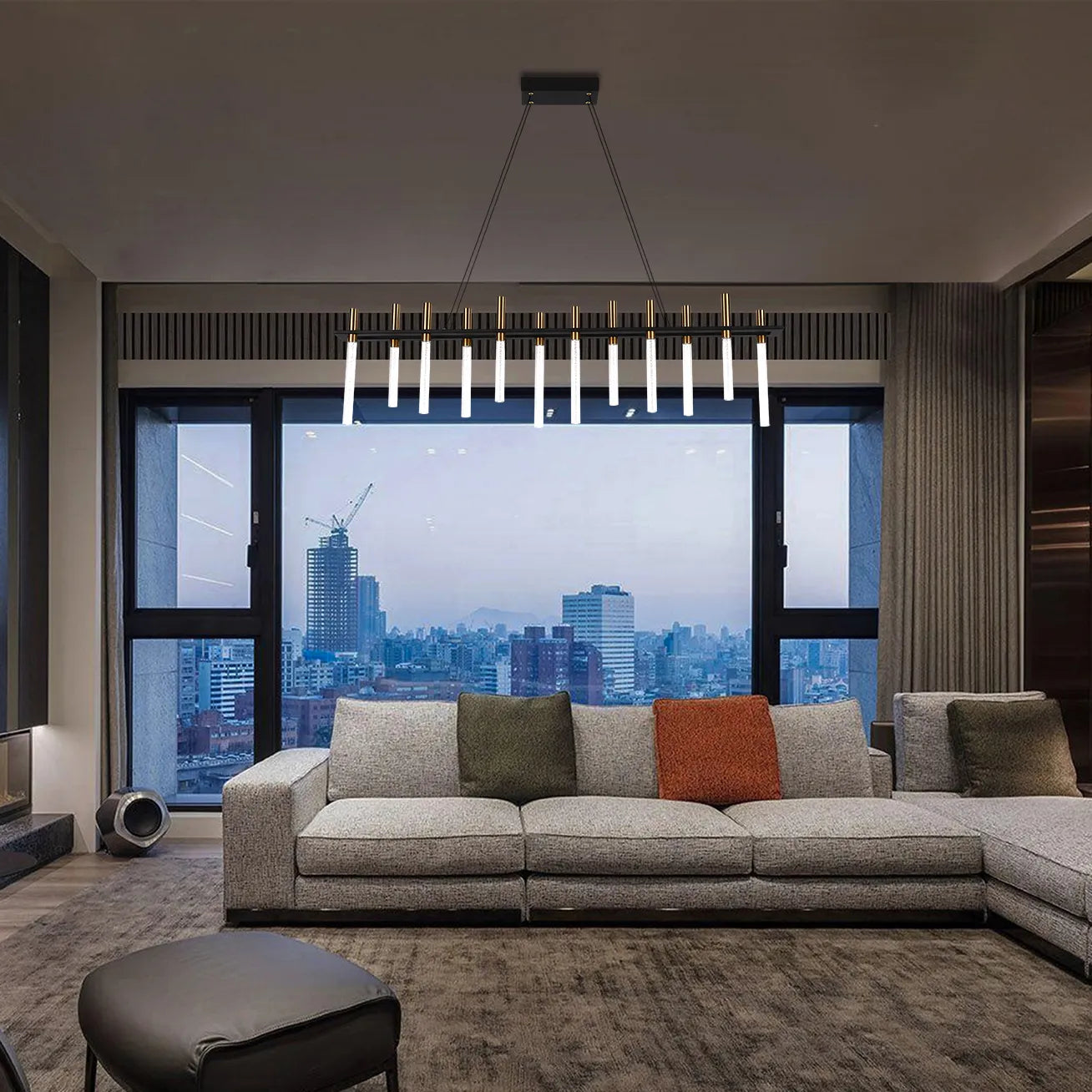 Modern linear chandelier with sleek black and gold finish, casting soft light in a contemporary living space.