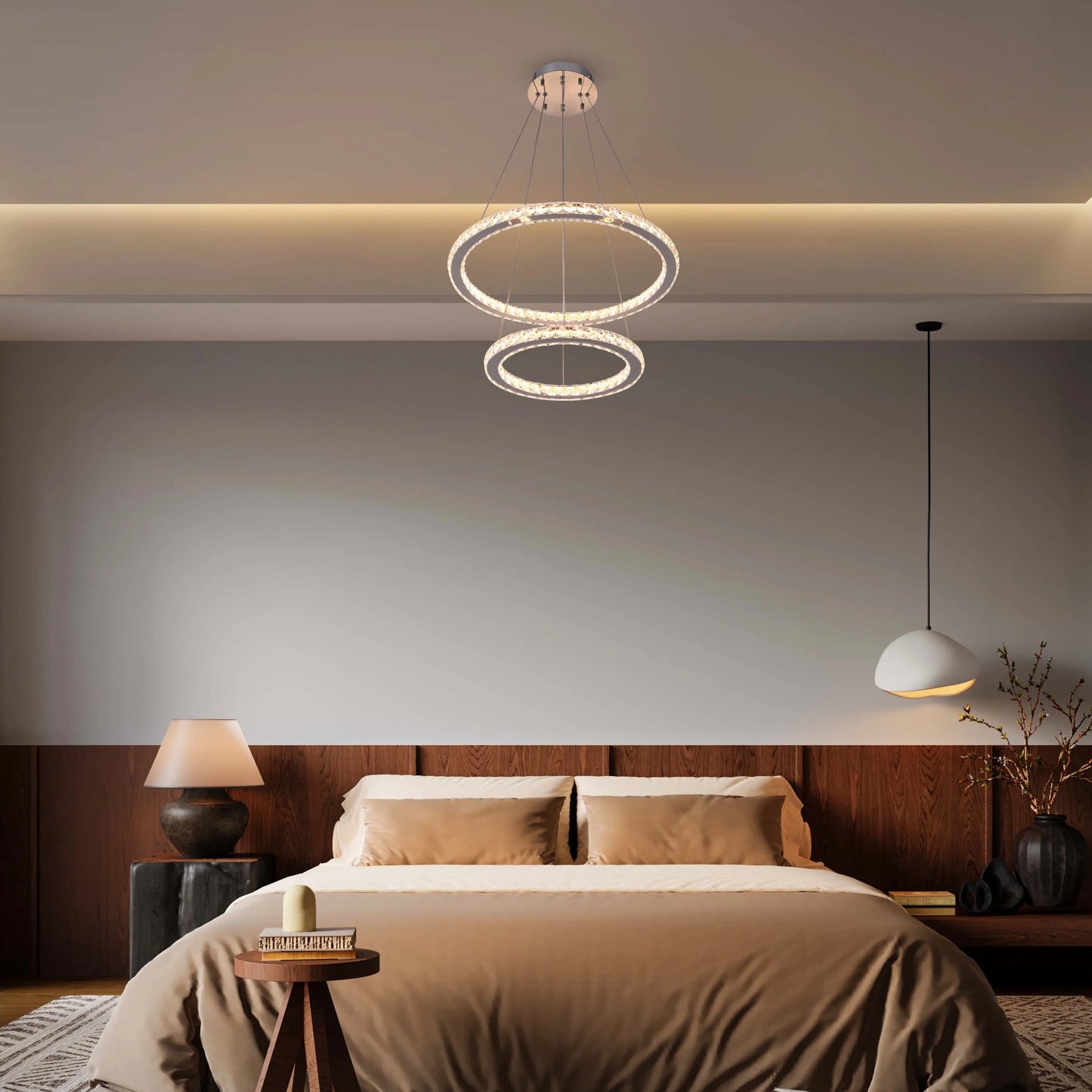 Modern bedroom featuring a dual-ring crystal chandelier, a pendant lamp, and a bedside table lamp, offering a warm ambiance.