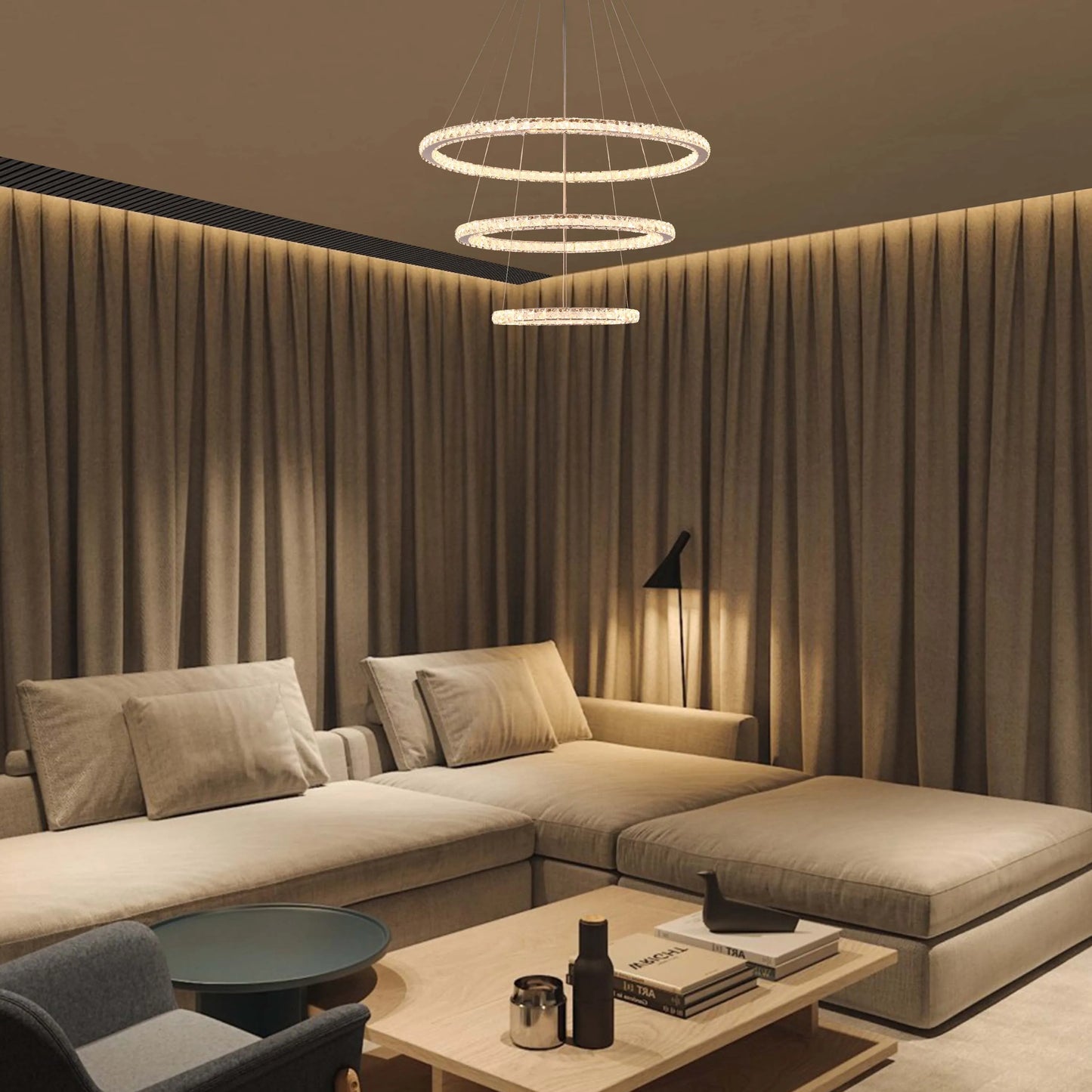 A contemporary multi-tiered ring chandelier, crafted with sparkling crystals, illuminates a modern living space with ambient light.
