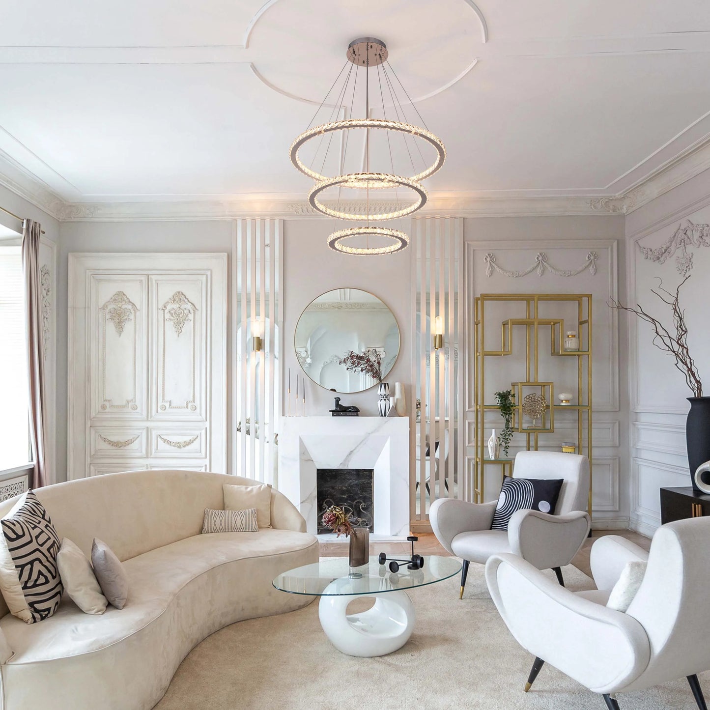 A modern living room features a glamorous three-tiered ring chandelier above a curved sofa, exuding luxury and style.