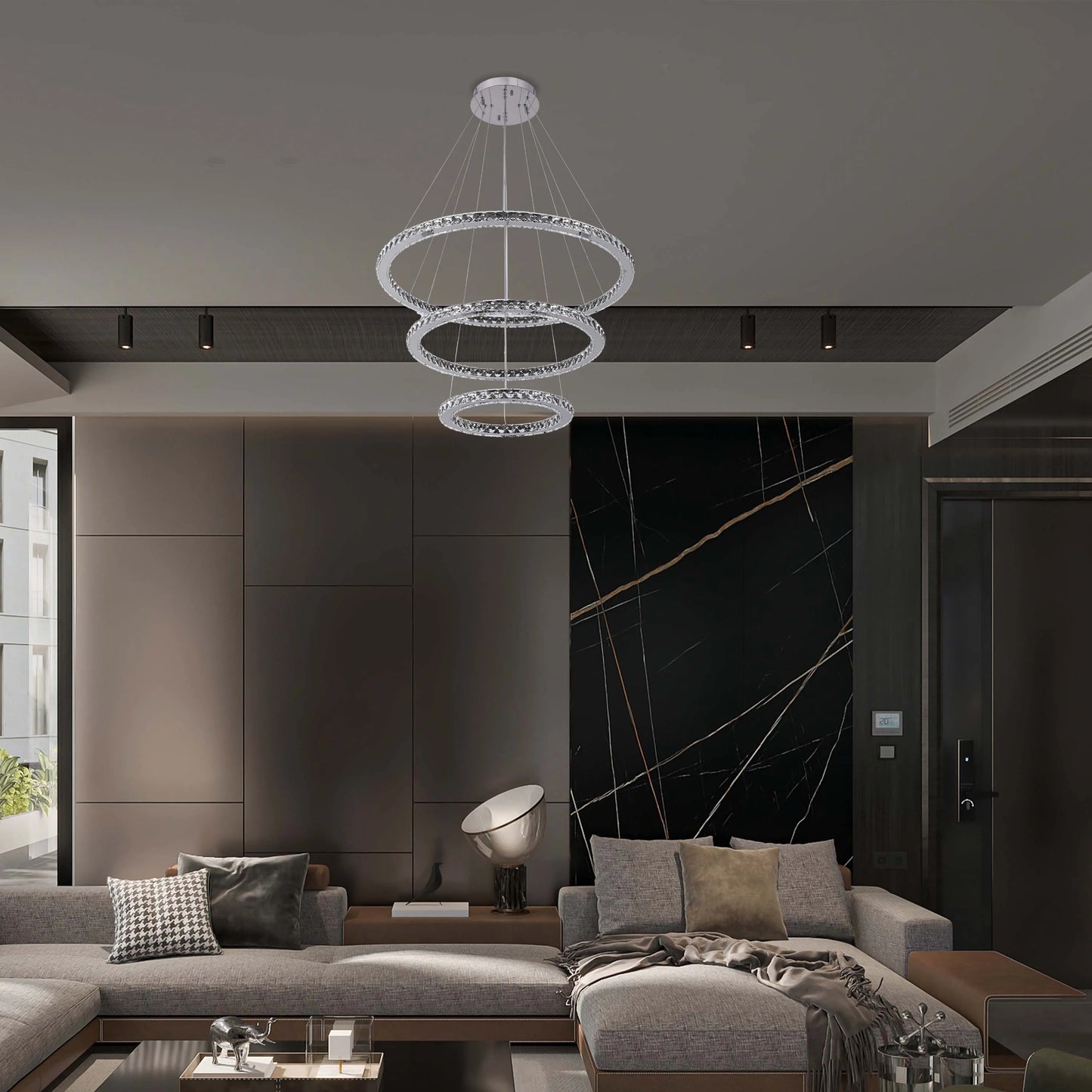 A modern three-tier circular chandelier hangs from the ceiling. Spotlights also feature in the dark wood panel above.