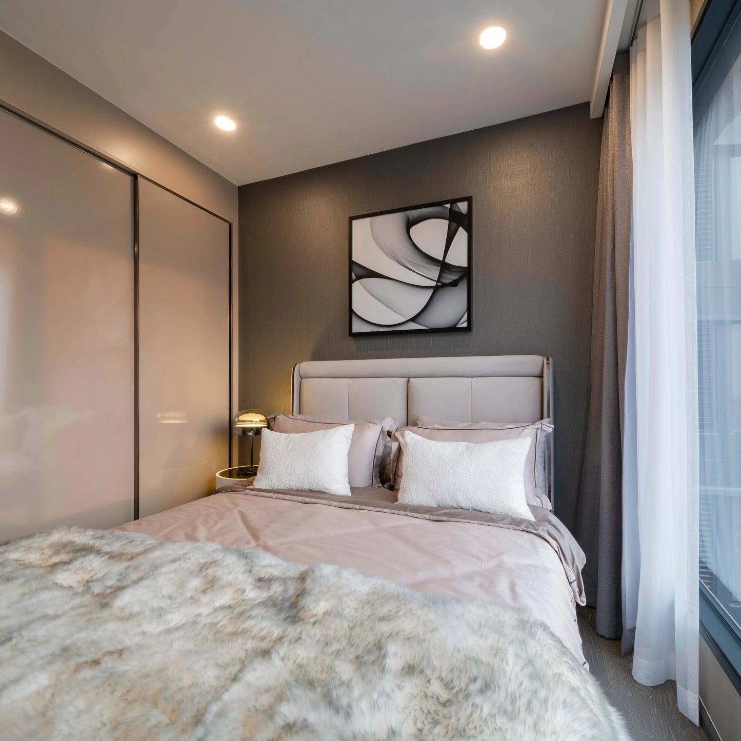 Bedroom with recessed ceiling lights illuminating the scene, complemented by a bedside table lamp for a warm, inviting ambience.
