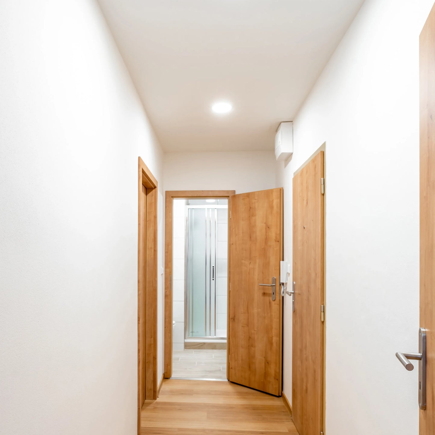 A well-lit hallway with a bright overhead light, showcasing a clean, modern aesthetic and warm illumination.