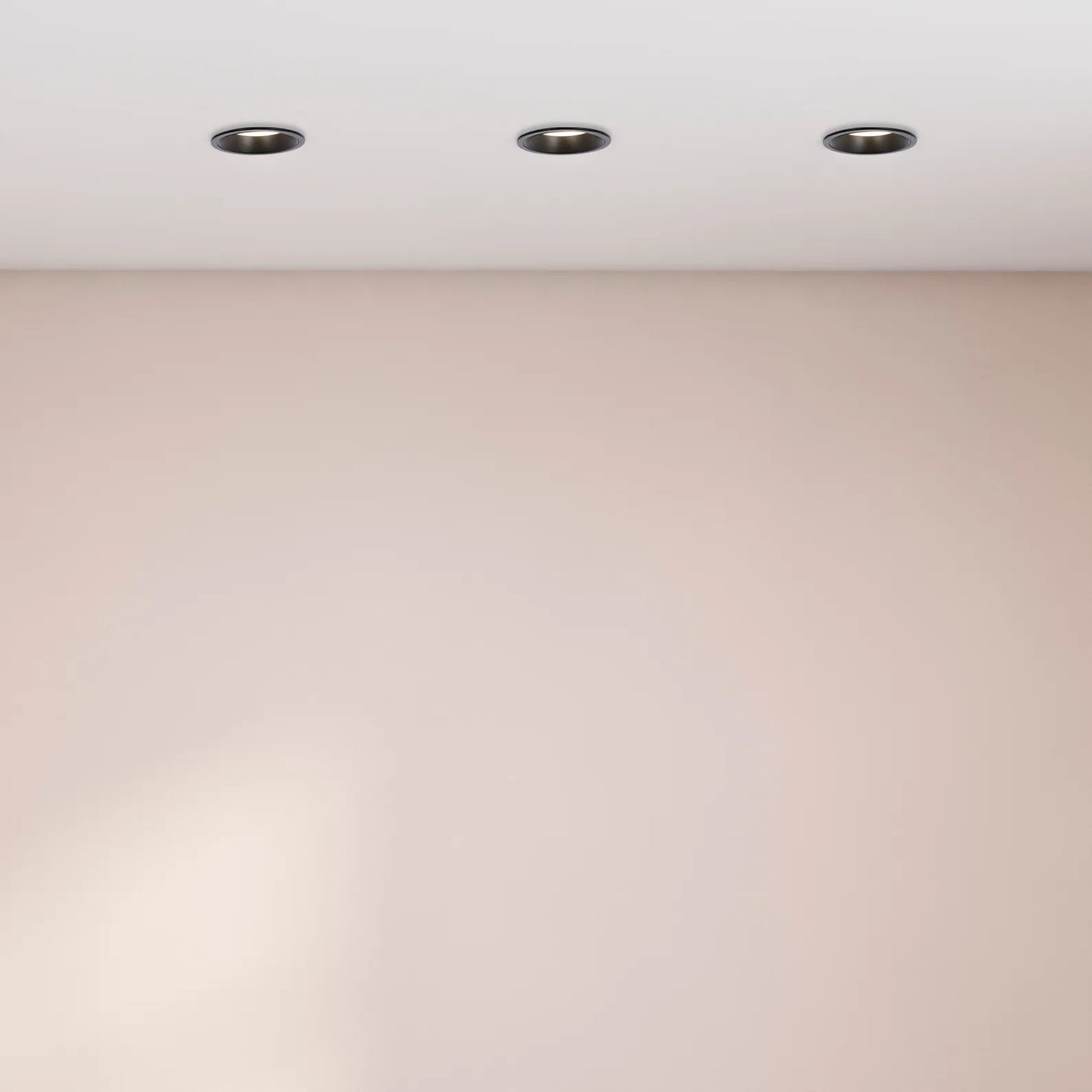 A clean interior view featuring three recessed ceiling lights illuminating a room with a soft, neutral wall colour.