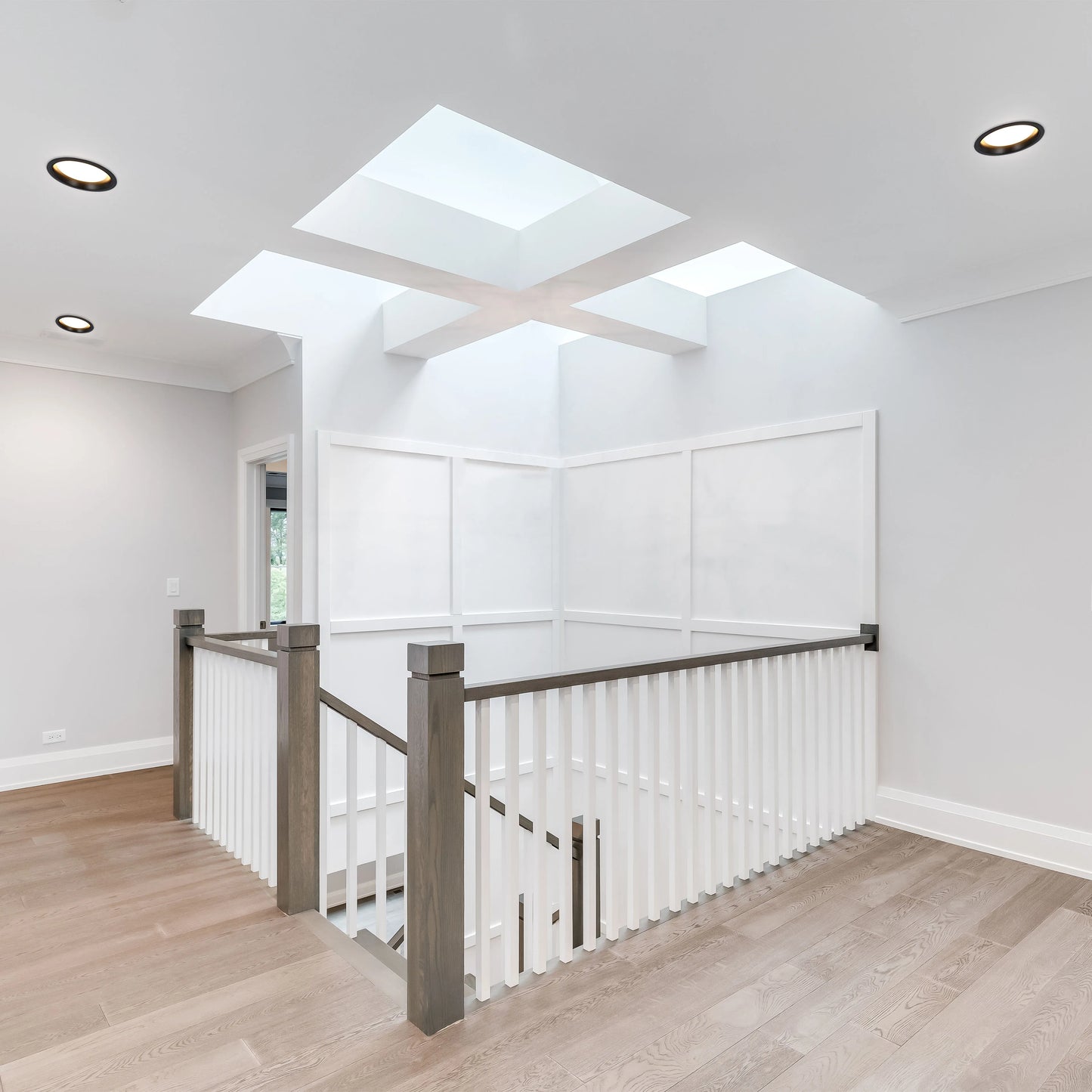 Bright lighting design with recessed ceiling lights and skylights creating a modern and airy atmosphere in this hallway.