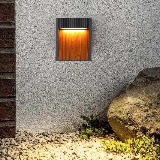 A stylish wall light emits a warm, inviting glow, highlighting the textured wall and adding ambience to the outdoor space.