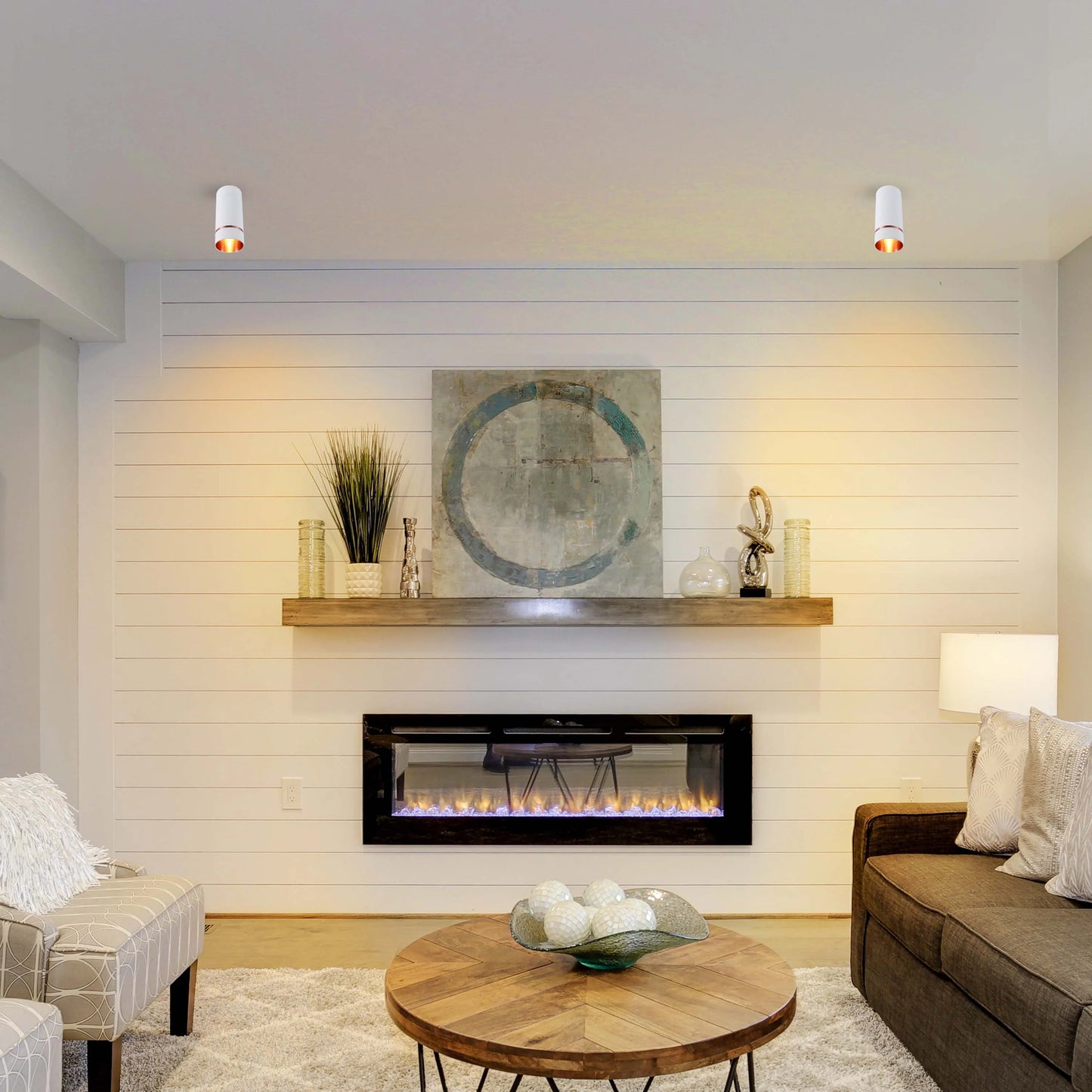 Modern downlights provide bright, focused illumination in this stylish living room, complementing the fireplace feature.