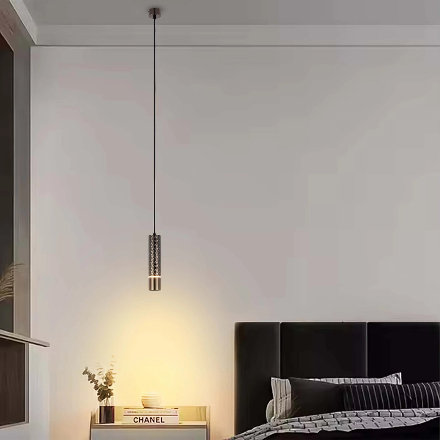 A modern pendant light fixture with a patterned shade, creating a warm and focused glow in a contemporary bedroom setting.