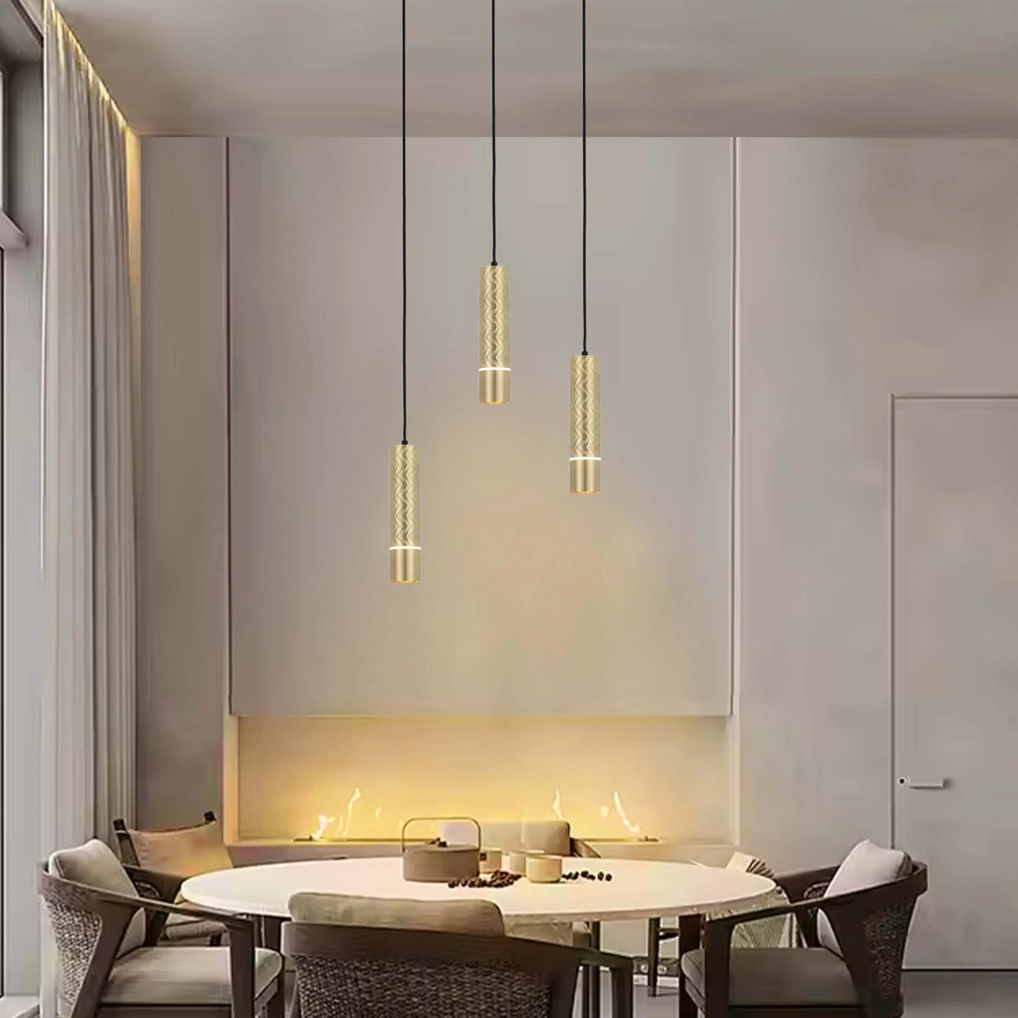 Stylish gold pendant lights hang above a dining table with a lit recessed fireplace behind in a modern dining room.