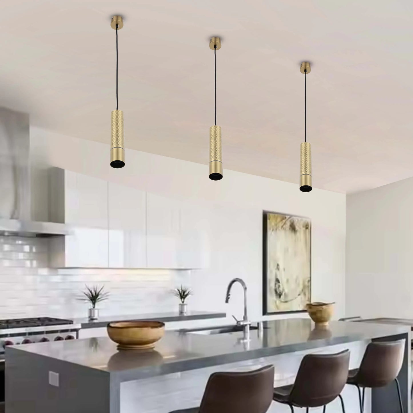 Three cylindrical, gold pendant lights hang above a kitchen island, creating a warm and modern atmosphere.