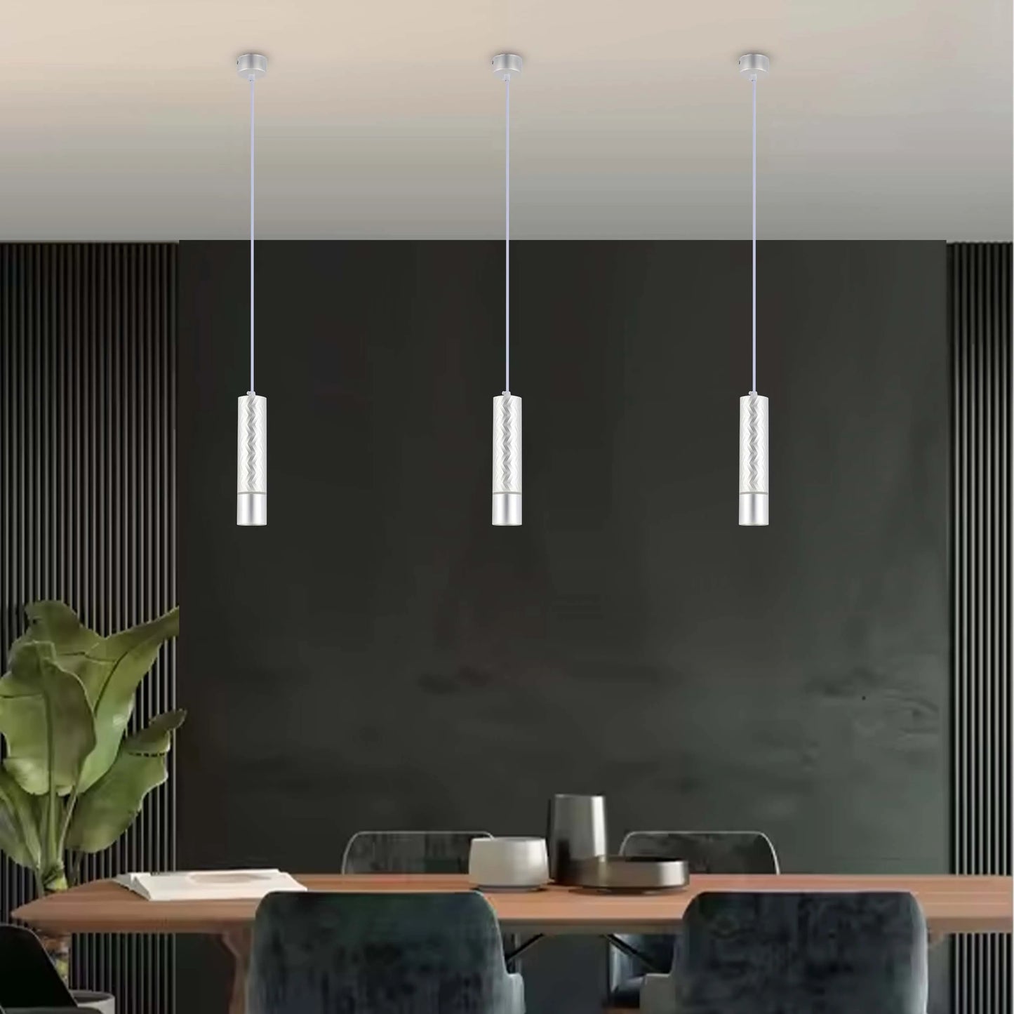 Three modern, cylindrical pendant lights hang above a dining table. These are silver, with a patterned design.