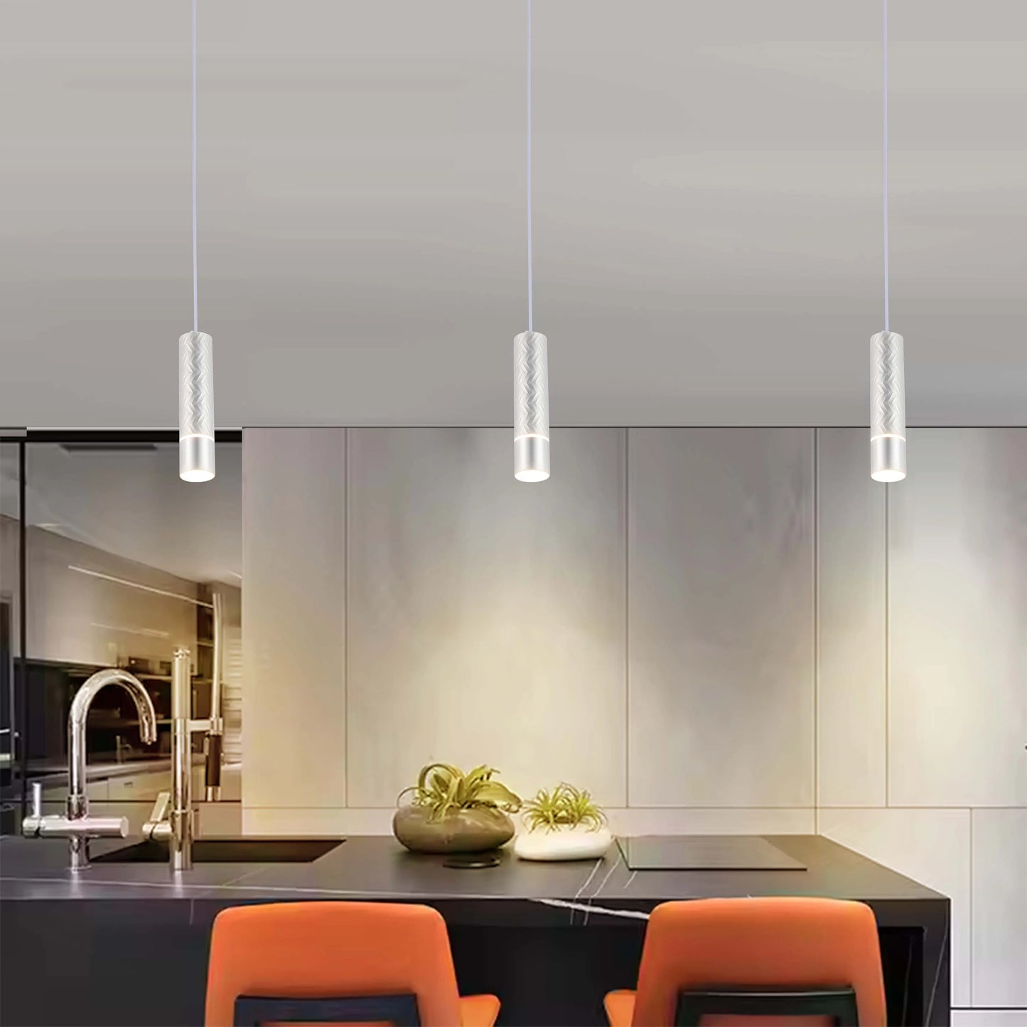 Three modern pendant lights hang above a kitchen island, illuminating the space with their sleek, cylindrical designs.