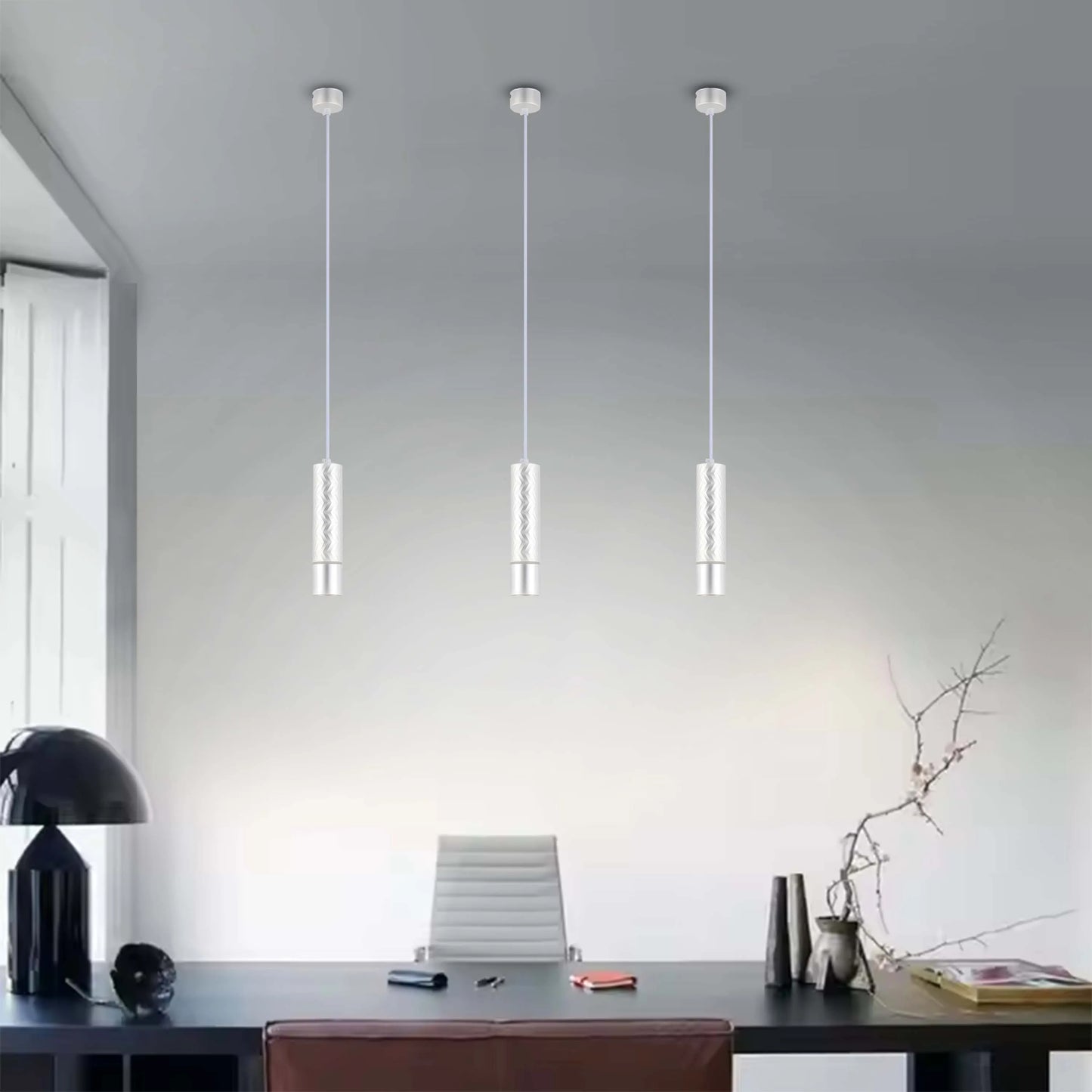 Contemporary lighting with three silver pendant lights hanging above a sleek desk, illuminating the modern workspace.