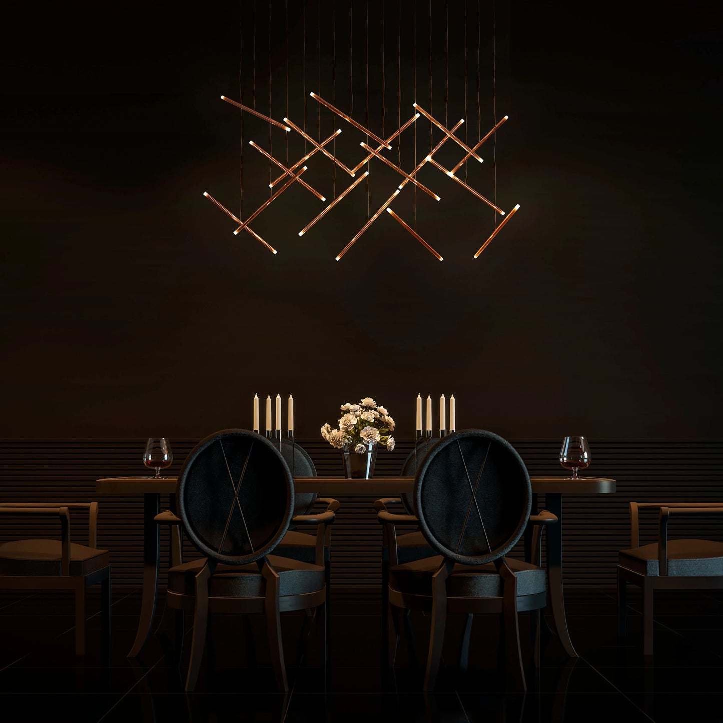 A modern chandelier made of interconnected golden rods provides ambient lighting above a dimly lit dining table.