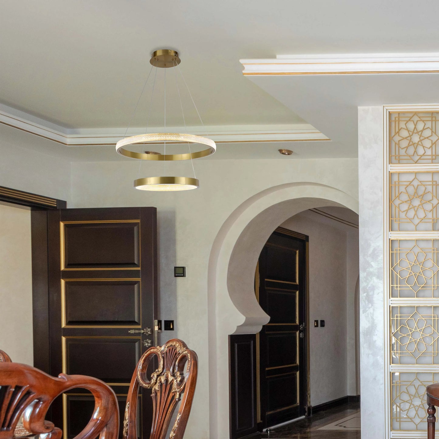 A modern, gold, two-tiered ring pendant light fixture illuminates an elegant dining room, complementing the ornate decor.