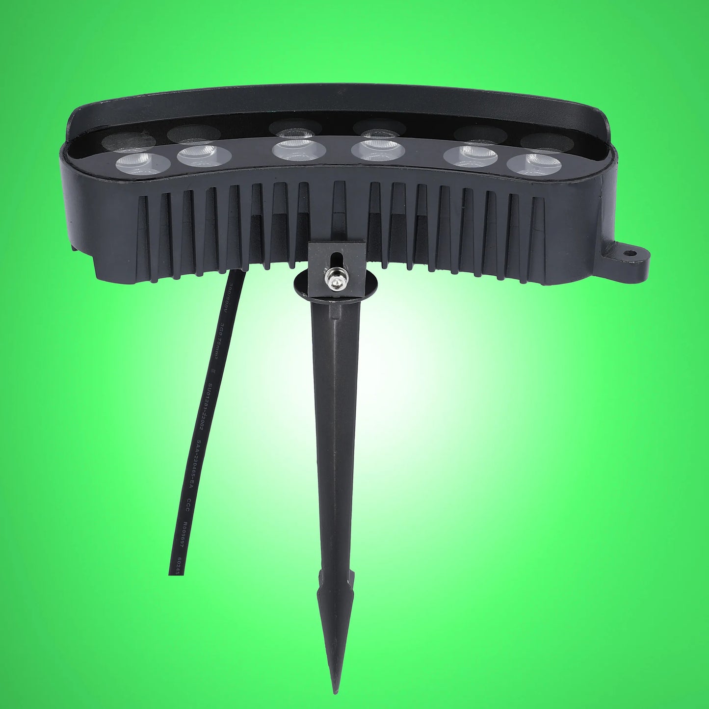 A close up of a black LED garden spotlight with a spike on a green background.