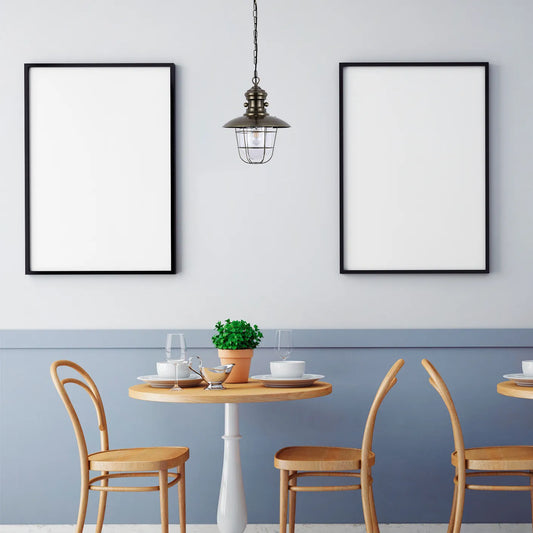 A stylish industrial pendant light fixture hanging above a set table, casting a warm glow in a contemporary dining space.