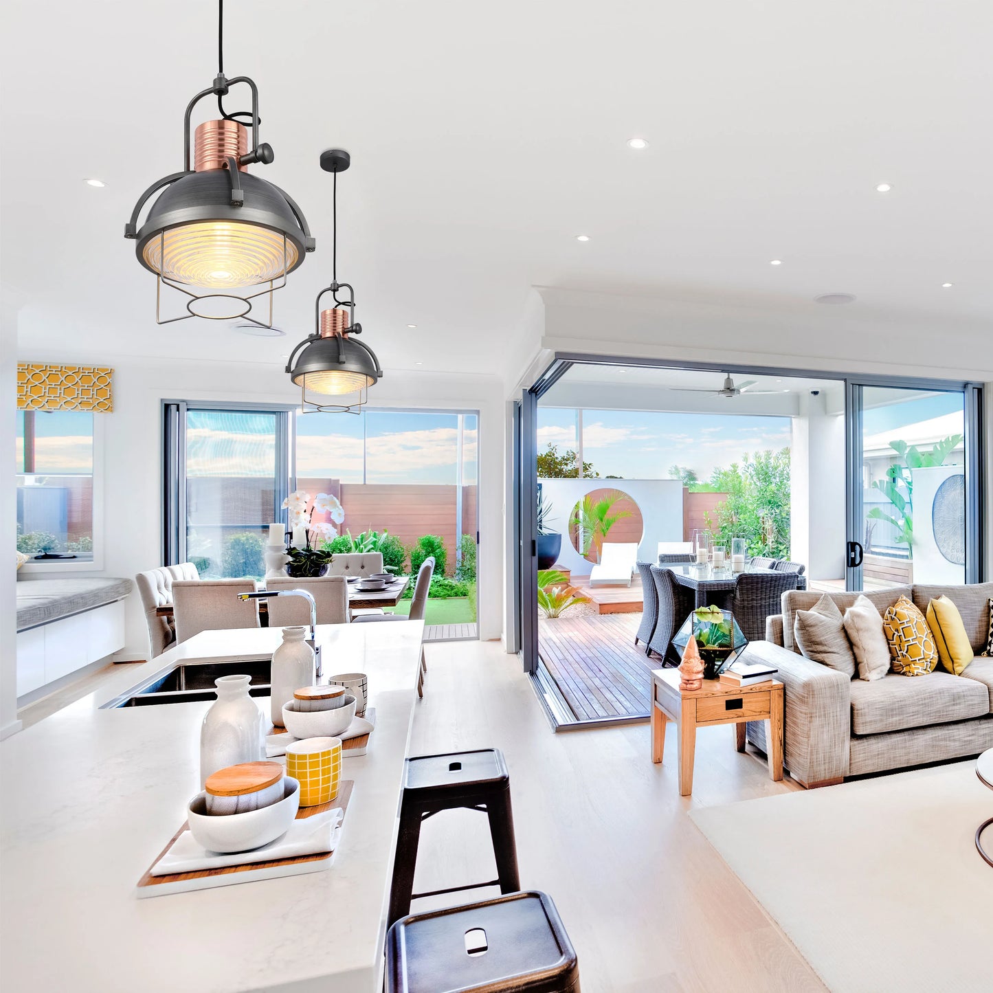 Industrial-style pendant lights hang above a kitchen island, adding a touch of modern charm to this bright, open-plan living space.