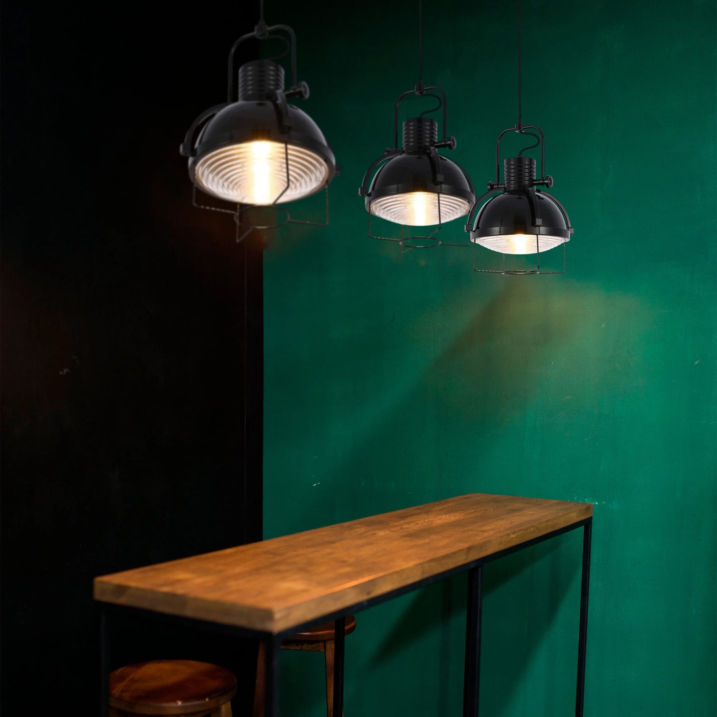 Three industrial-style pendant lights with black metal shades illuminate the space with a warm glow, creating a cosy ambience.