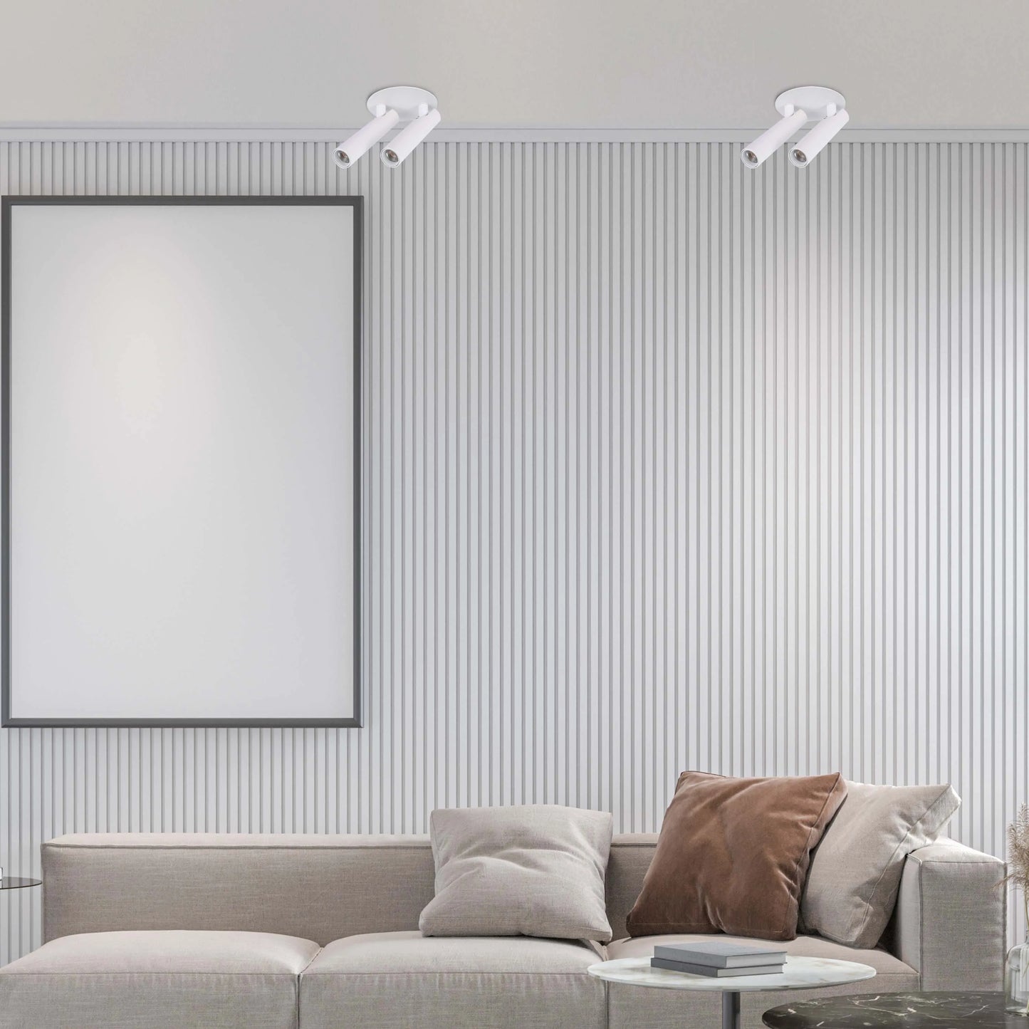 Minimalist white spotlights illuminate a living room with a blank framed poster above a modern sofa and side tables.