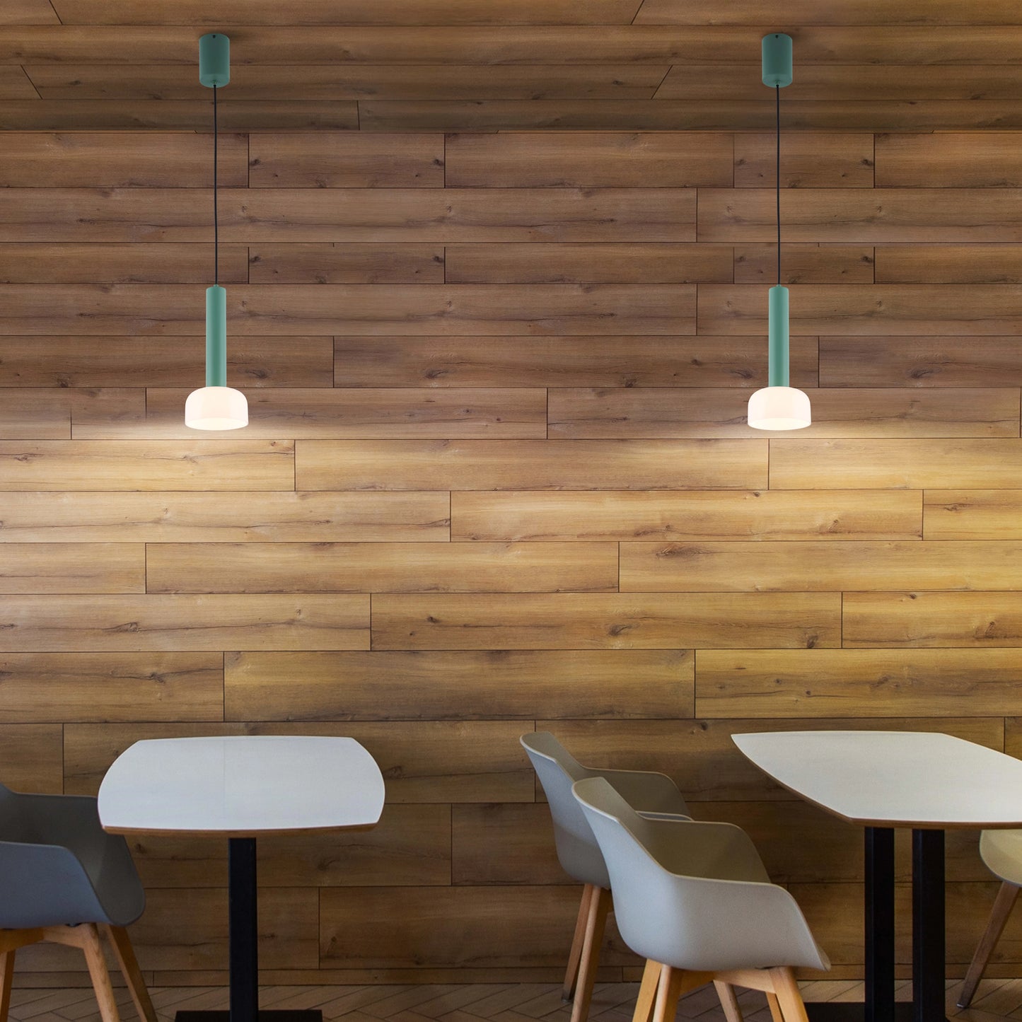Two green pendant lights hang from the ceiling, illuminating a stylish cafe setting with a warm and inviting atmosphere.