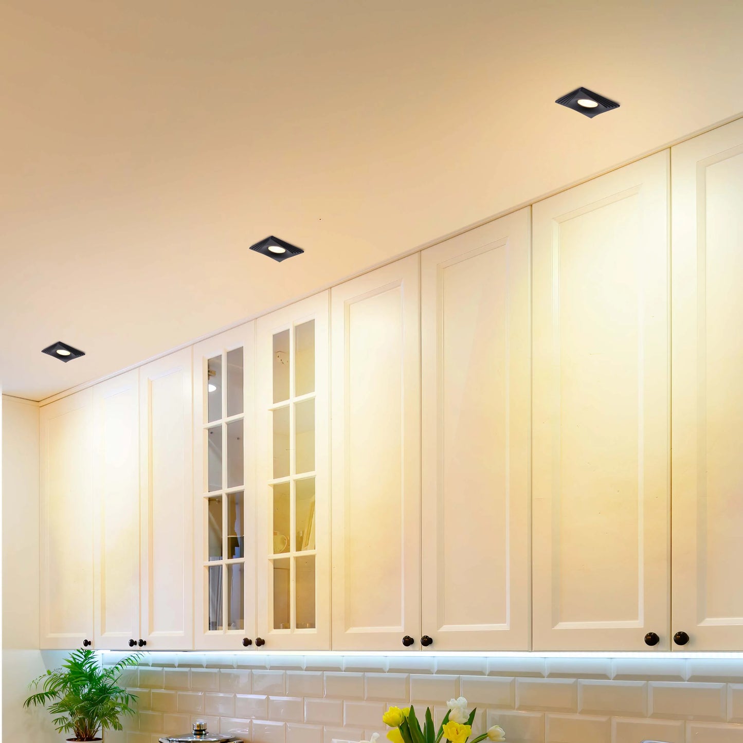 Stylish kitchen with square, recessed ceiling lights and under-cabinet lighting providing bright, modern illumination.