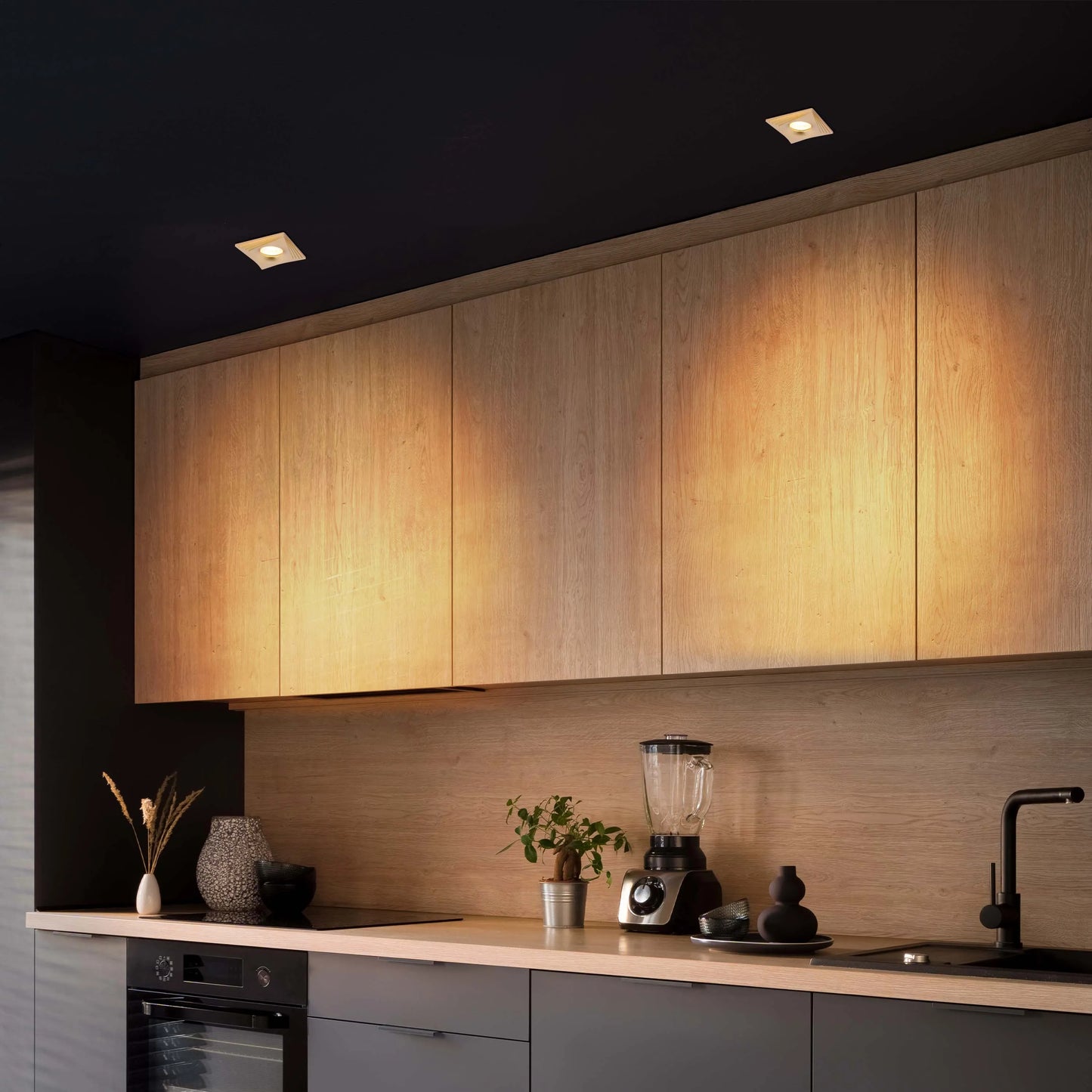 Warm, ambient lighting illuminates the kitchen, creating a welcoming atmosphere with recessed ceiling lights and under-cabinet glow.