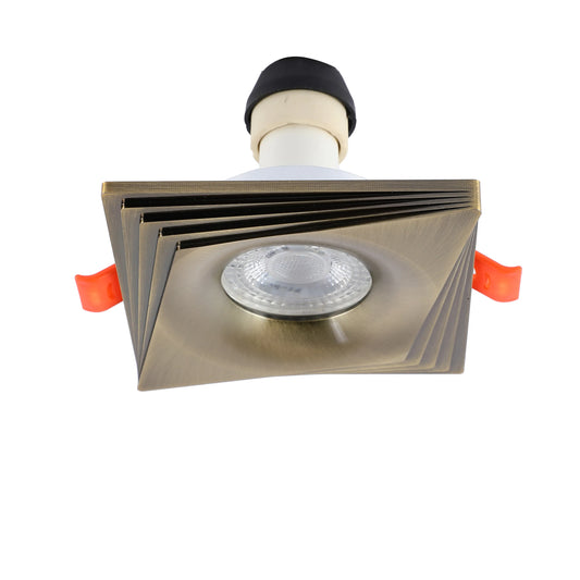 Close up of a square recessed spotlight with a gold finish and transparent lens.