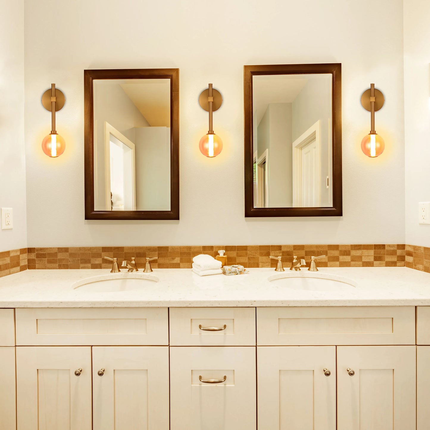 A bathroom with two brown-framed mirrors and three globe-shaped vanity lights.