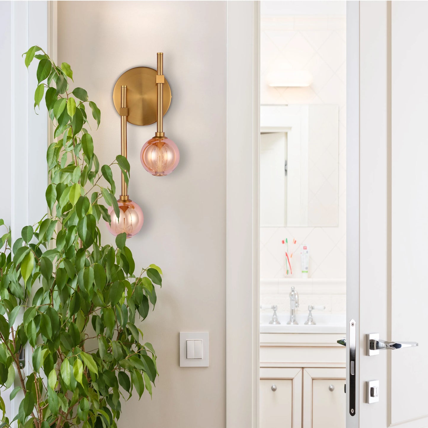 A stylish wall light with a brass finish and two pink glass globes, creating a warm and inviting atmosphere.