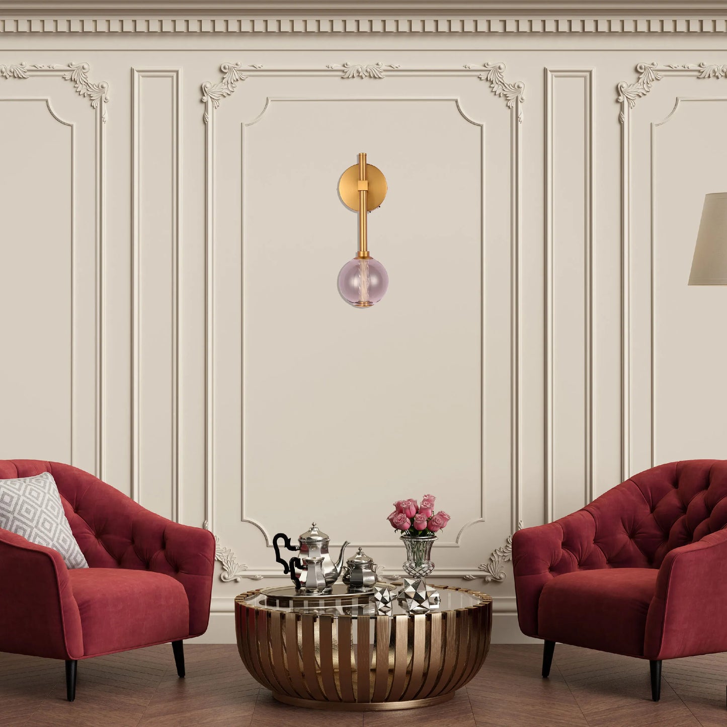 A decorative wall light featuring a gold fixture with a single, round glass shade in a soft pink hue.