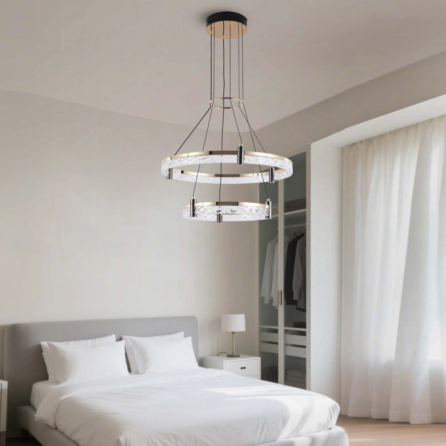 A two-tier crystal chandelier hangs in a neutral bedroom, providing ambient light with a touch of modern elegance.