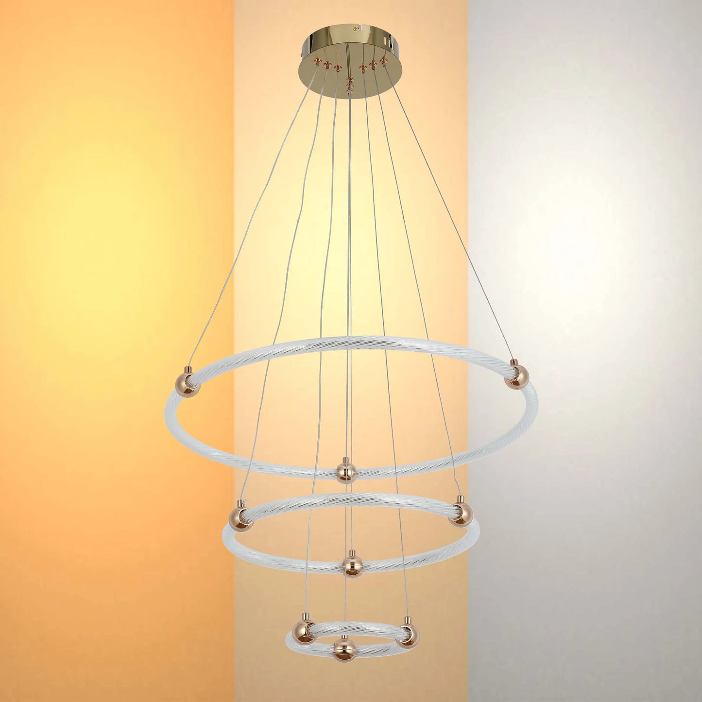 A modern multi-tier LED chandelier with circular frosted glass rings and brushed gold fittings, against a neutral coloured backdrop.