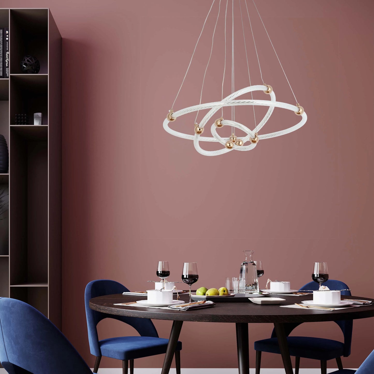 A stylish, contemporary pendant light featuring intertwined white rings and gold accents, suspended above a dining table set for a meal.