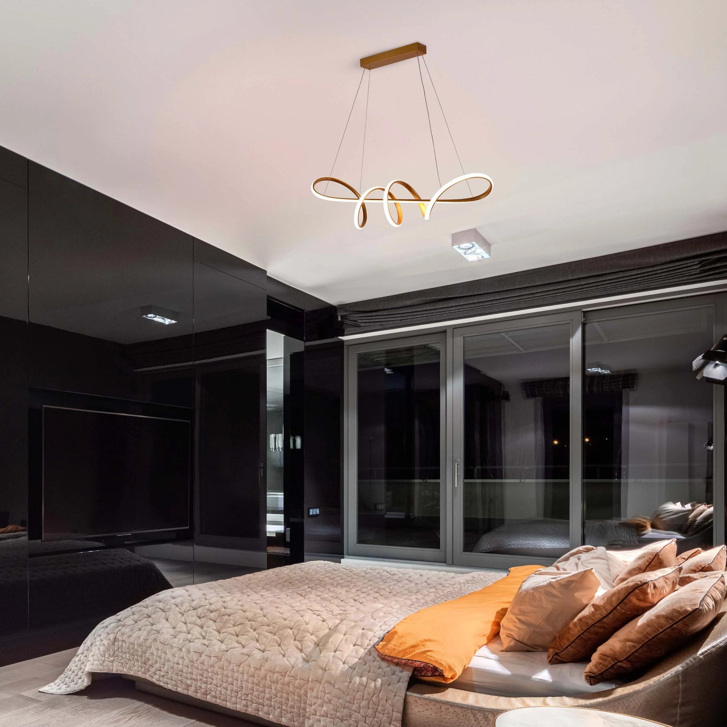 A modern bedroom pendant light fixture, with gold hardware and integrated LED lighting, illuminates the space.