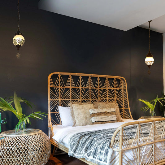 A bedroom with wicker furniture is lit by ornate pendant lights, creating a cosy, inviting ambience with warm, ambient lighting.