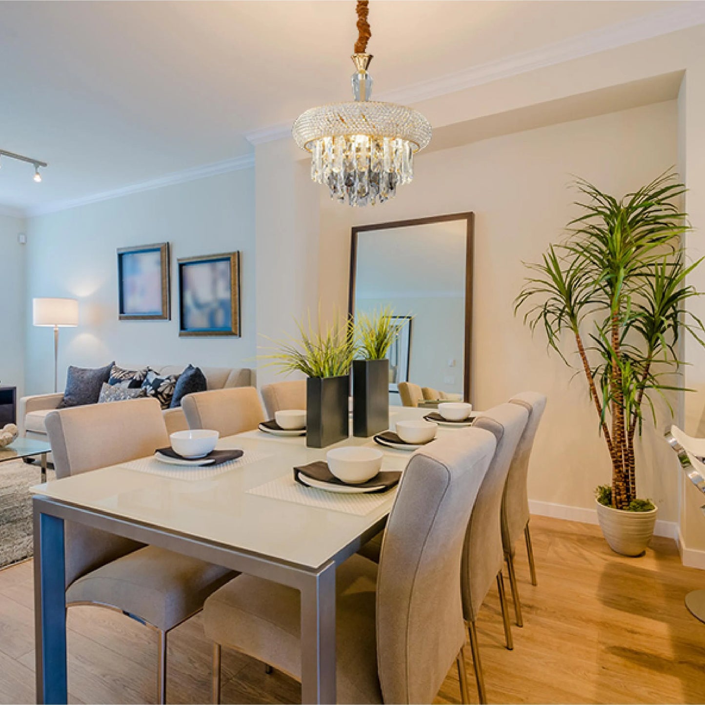 A glamorous chandelier hangs above a dining table, adding elegance with its cascading crystals and sparkling light in a modern interior.
