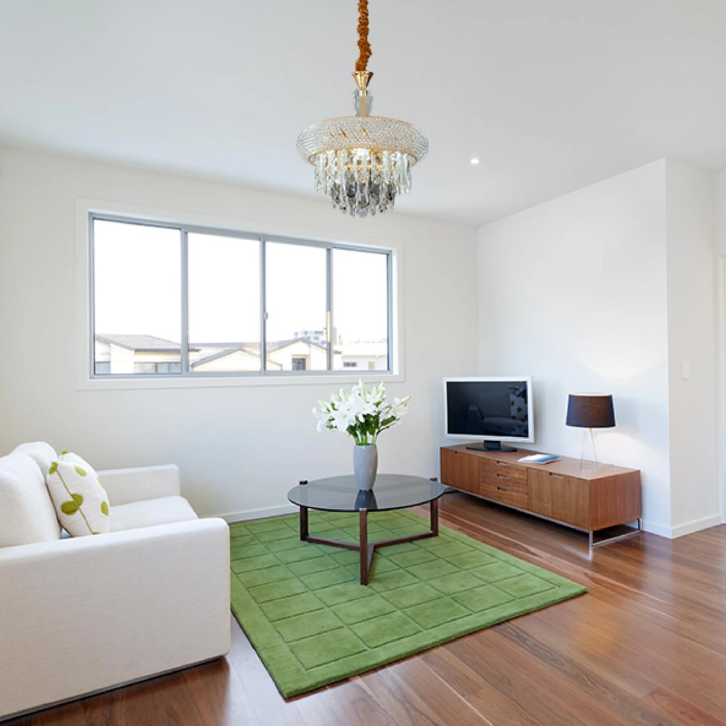A crystal chandelier illuminates a modern living room, showcasing elegant overhead lighting.