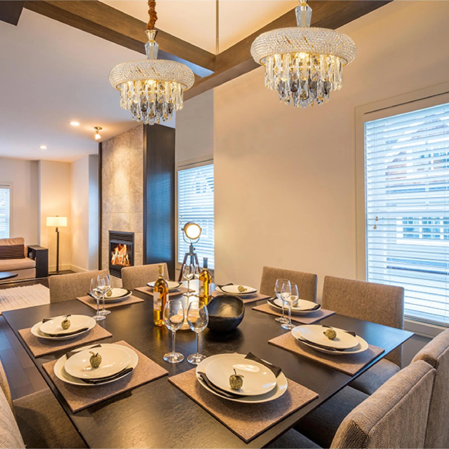 Two crystal chandeliers illuminate a dining table set for eight. A standing lamp and fireplace provide additional light.