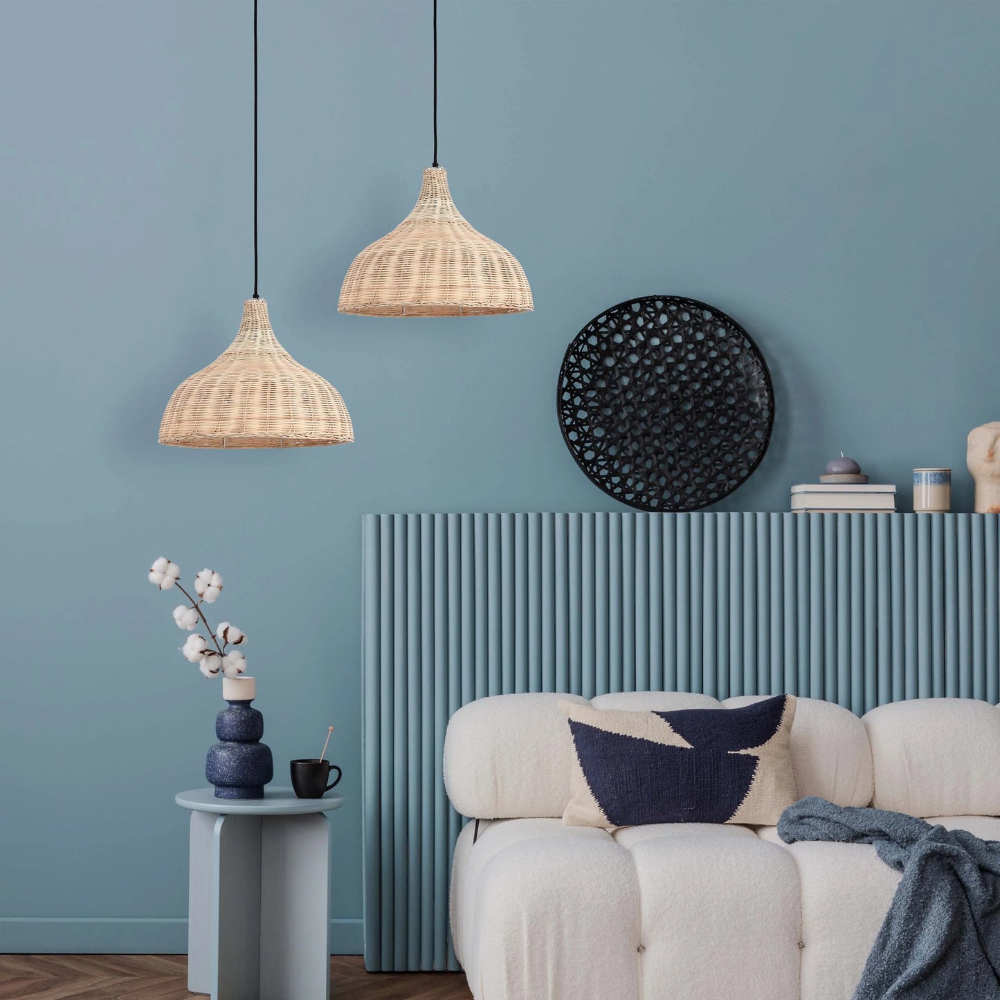 Two rattan pendant lights hang above a stylish living area with a textured sofa, blue accents and contemporary decor.