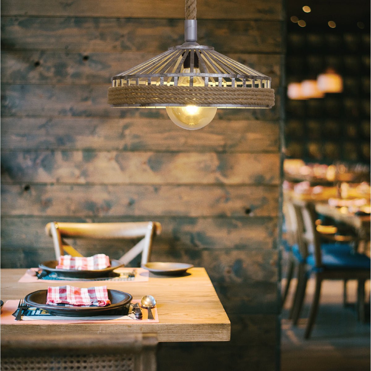 Wooden table is set, chairs visible. Rustic light fixture hangs above. Warm and inviting dining area.