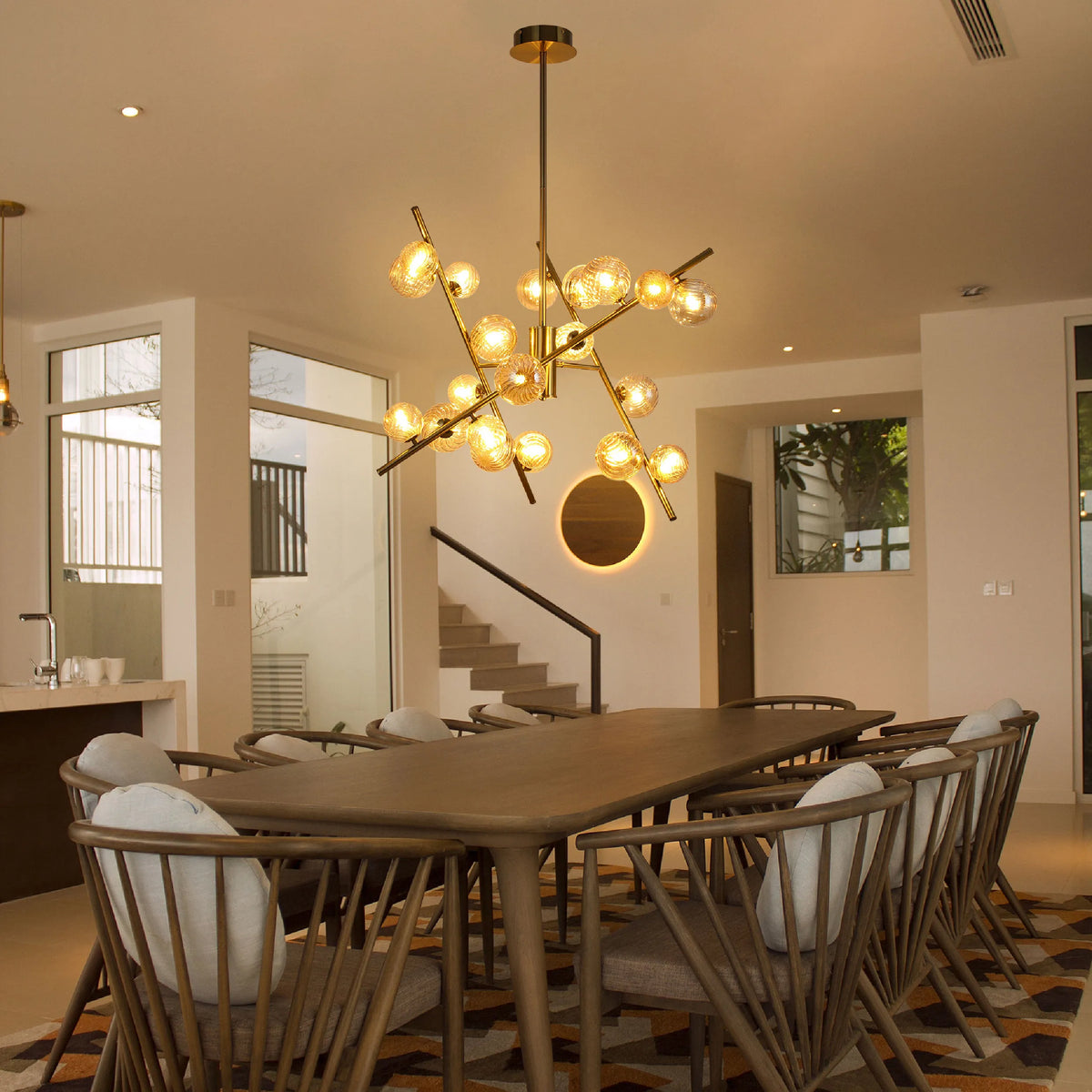 A striking gold sputnik chandelier hangs above a wooden dining table, providing warm, ambient lighting in a modern dining space.