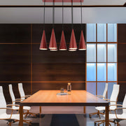 Statement lighting in a modern office space. Striking, geometric, red pendant lights hang over a wooden conference table.