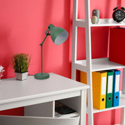 A green desk lamp illuminates a study space. The bright light showcases a modern, minimalist design.